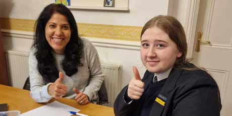 Neelu and one of her pupils smiling and giving a thumbs up during a maths lesson